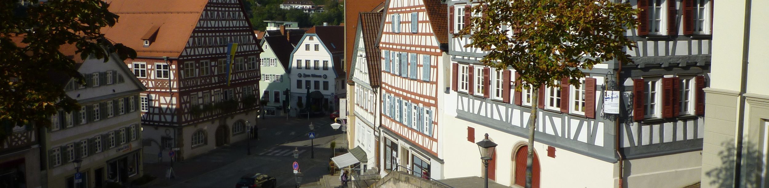 Marktplatz mit Fachwerkhäusern und roten Ziegeldächern sowie grünem Kirchturm
